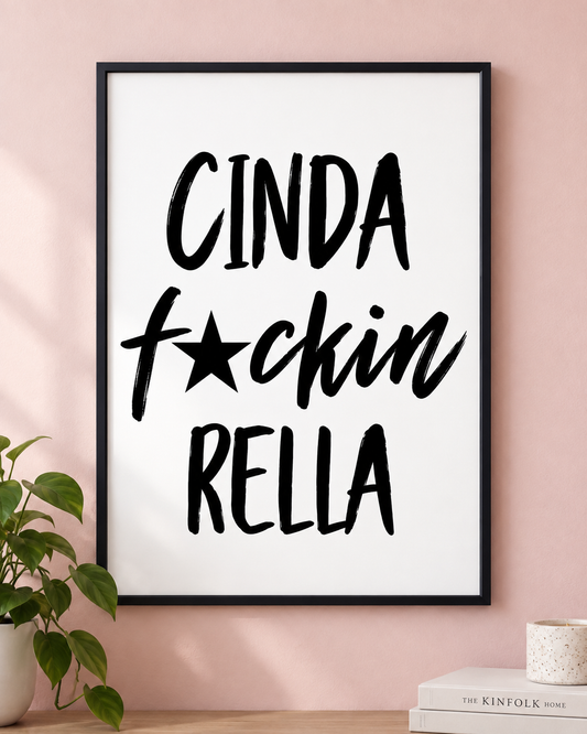 Cinda F★ckin Rella black-and-white typography print in a black frame, shown straight on against a pink wall